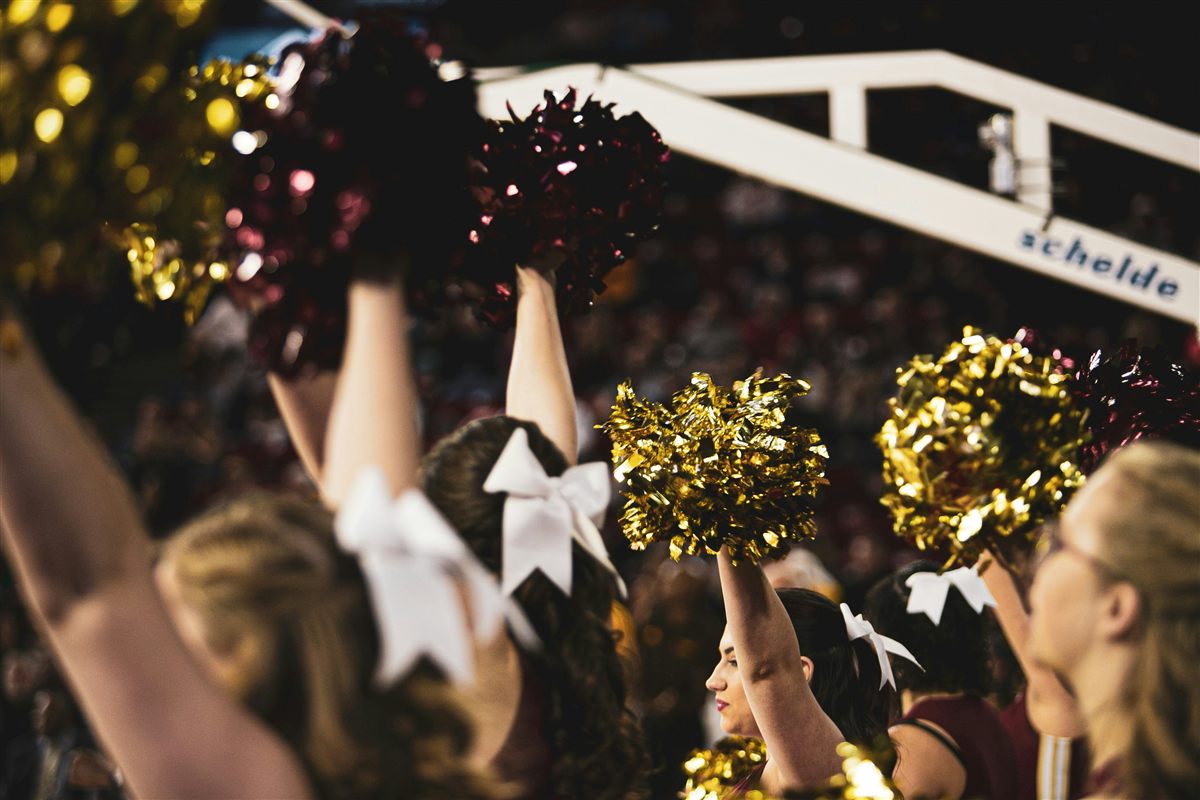 Cheerleaders raising gold and maroon pom-poms