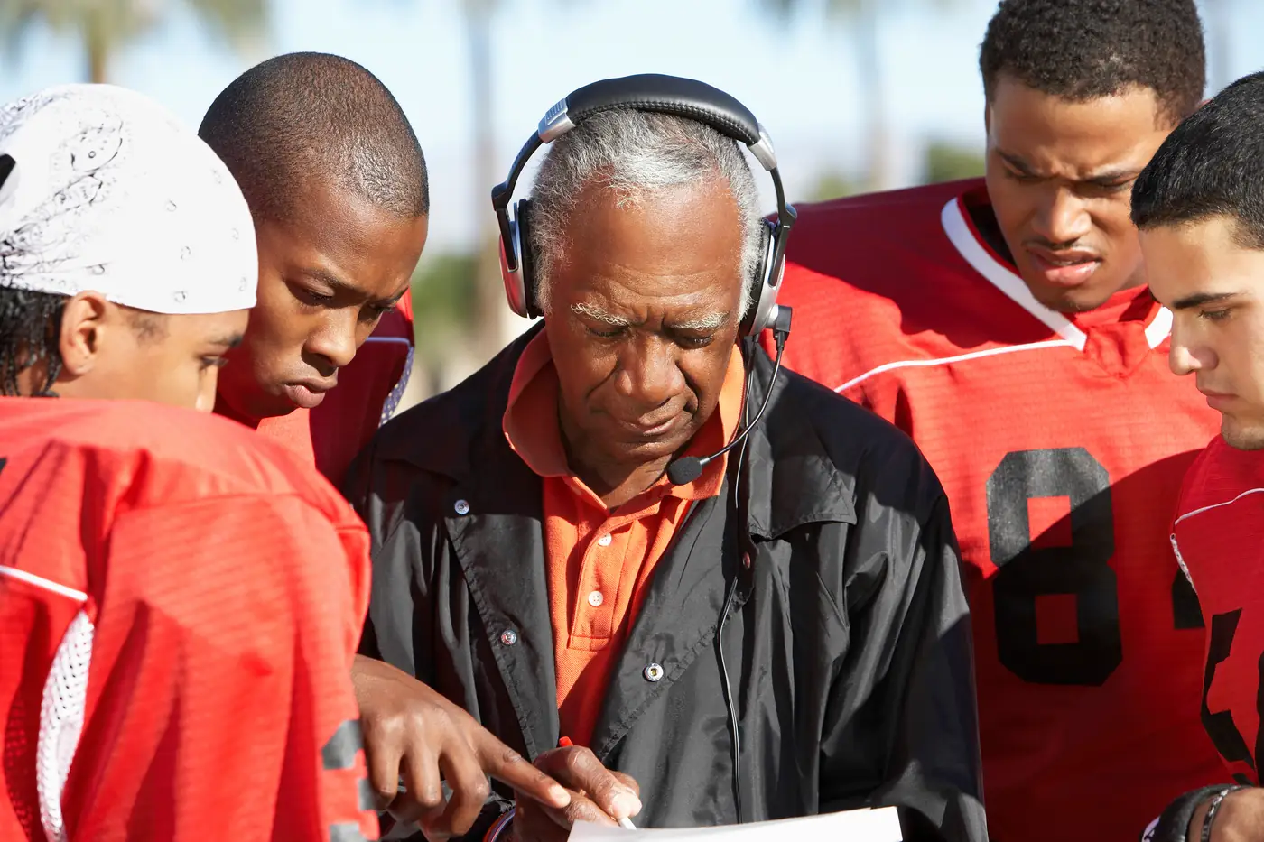 Coach reviewing a play sheet with his players