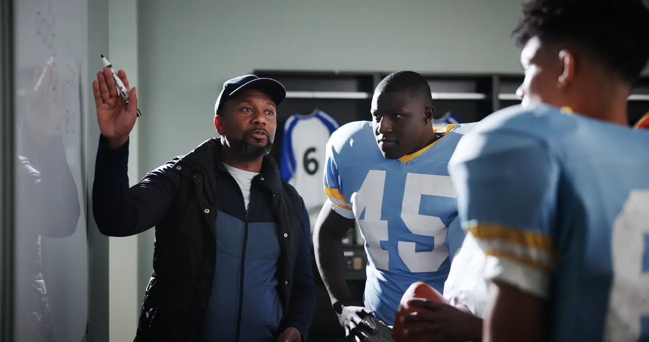 Coach drawing up a play for his players in a locker room