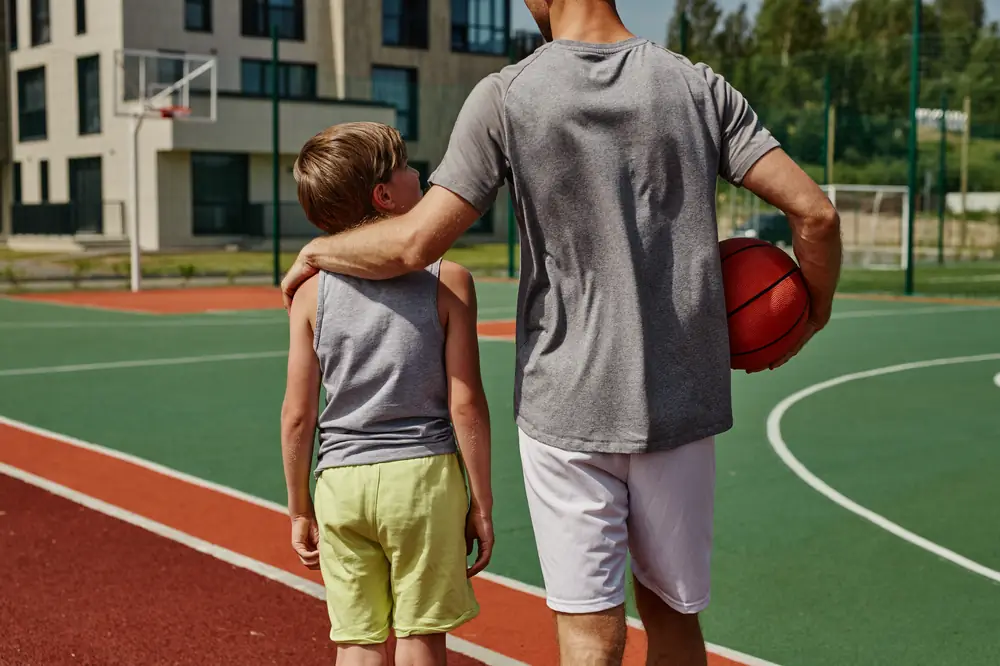 Parent walking onto a basketball court with a young player
