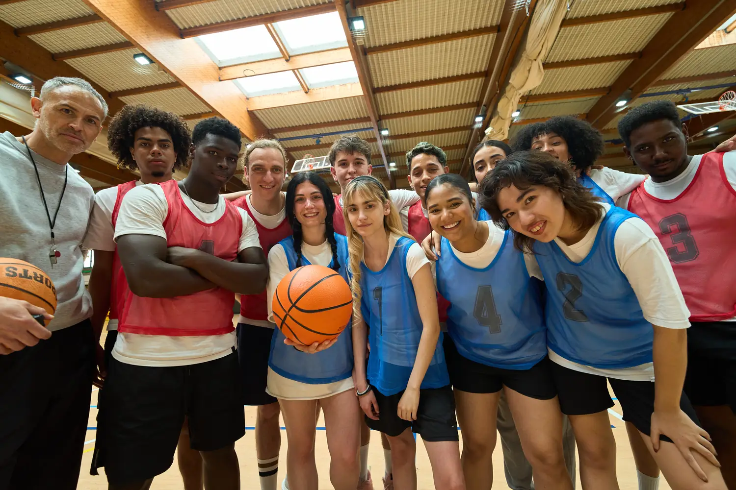 Coach and team posing together on a basketball court